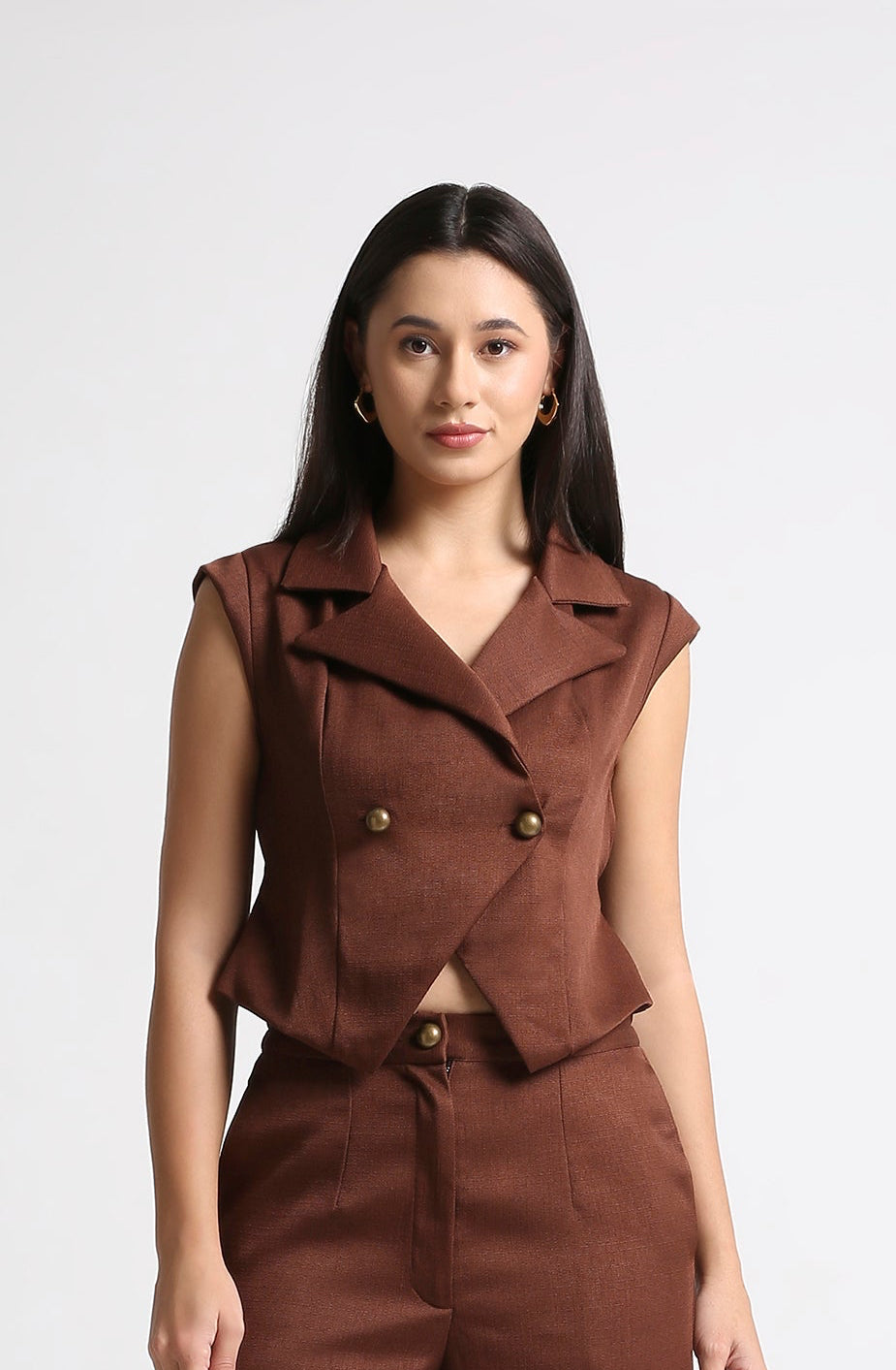 Woman wearing a brown sleeveless jacket and pants on a white background